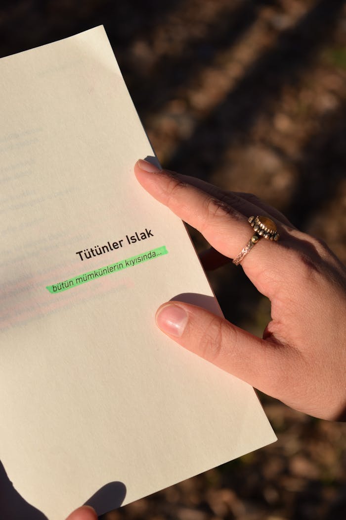 Hands holding a page with text in sunlight outdoors, creating a warm and intimate atmosphere.
