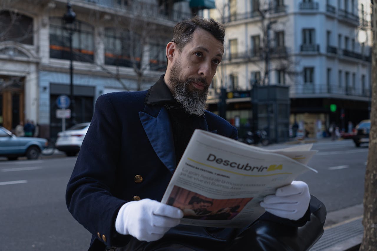 A man in formal attire reads a newspaper on a street in Buenos Aires, Argentina.